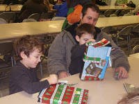 Adult and two children opening gifts at least two wrapped gifts