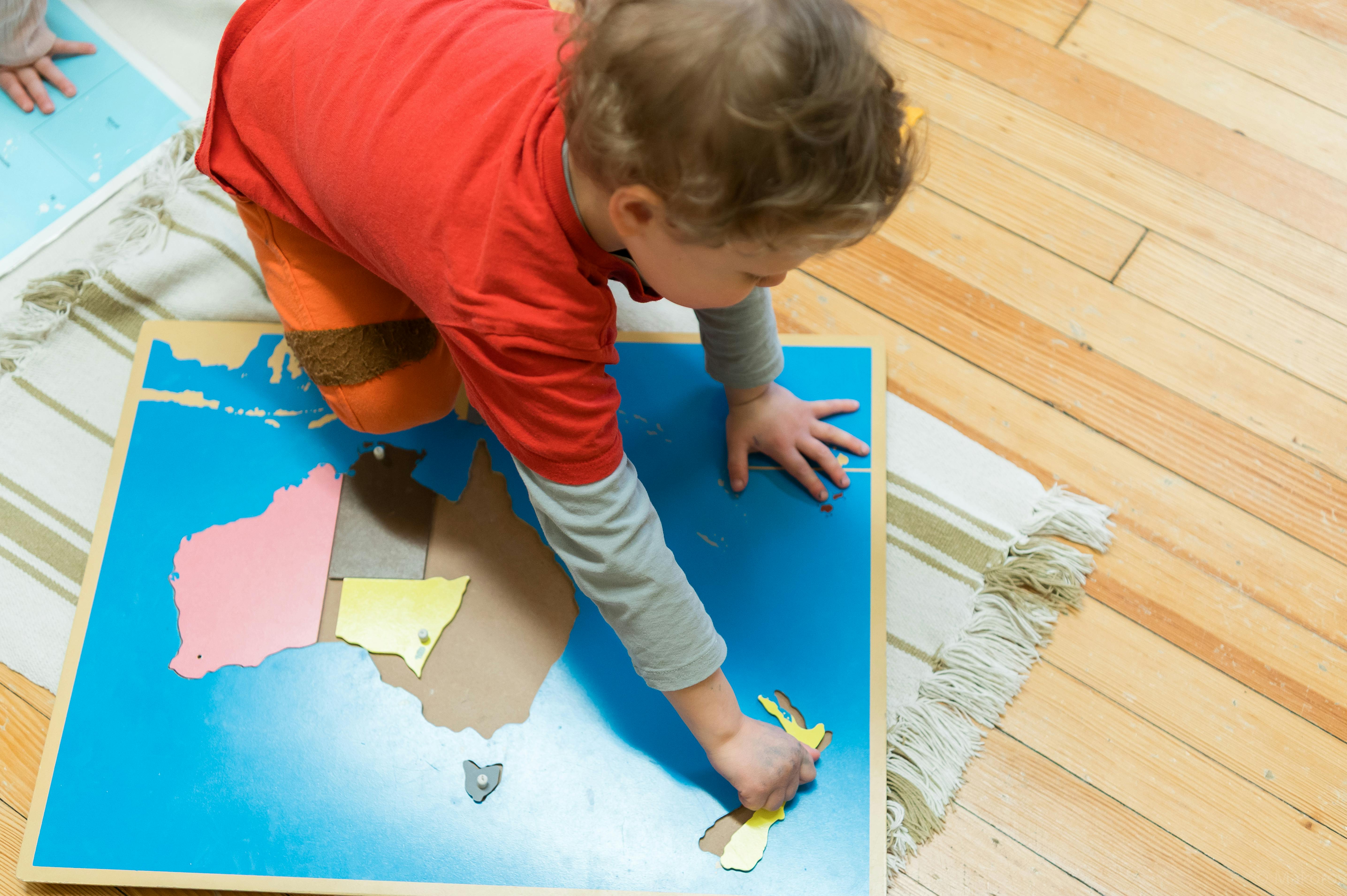 Child playing with a puzzle map on the floor