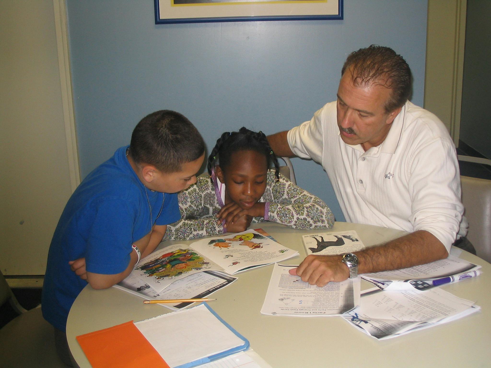 Adult and two children looking at books and papers on a table