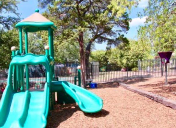 Playground with green slides and wood chips