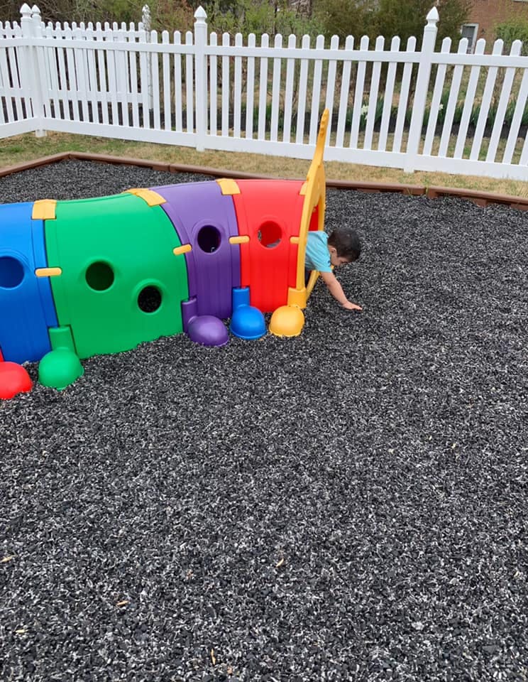 Child crawling out of a colorful play tunnel on a playground