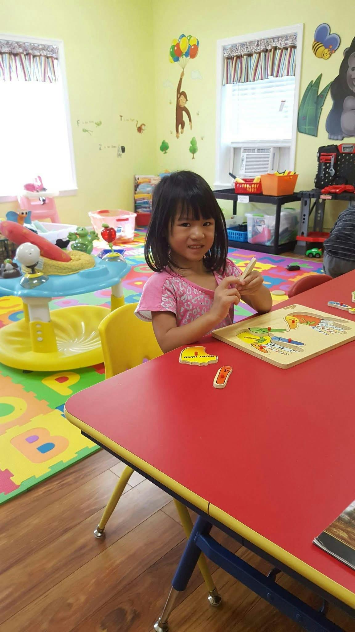 Child playing with a puzzle at a table in a playroom