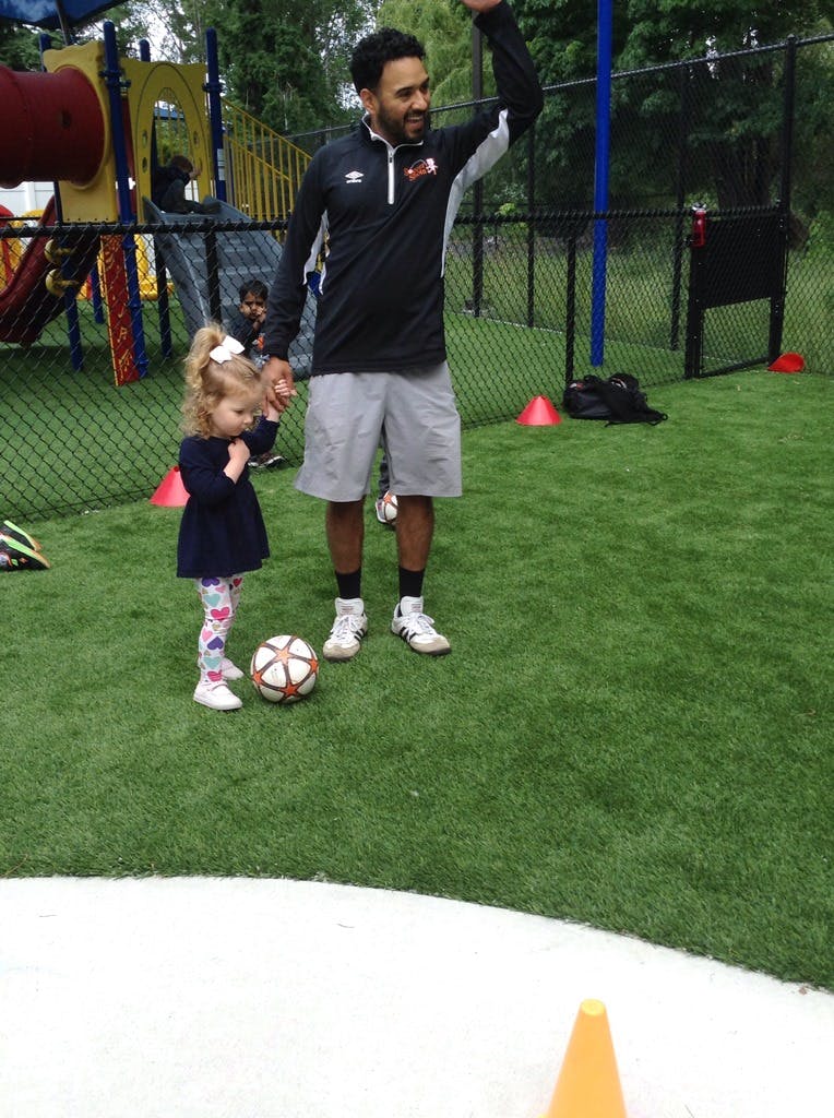 Adult and child on a grassy field with a soccer ball