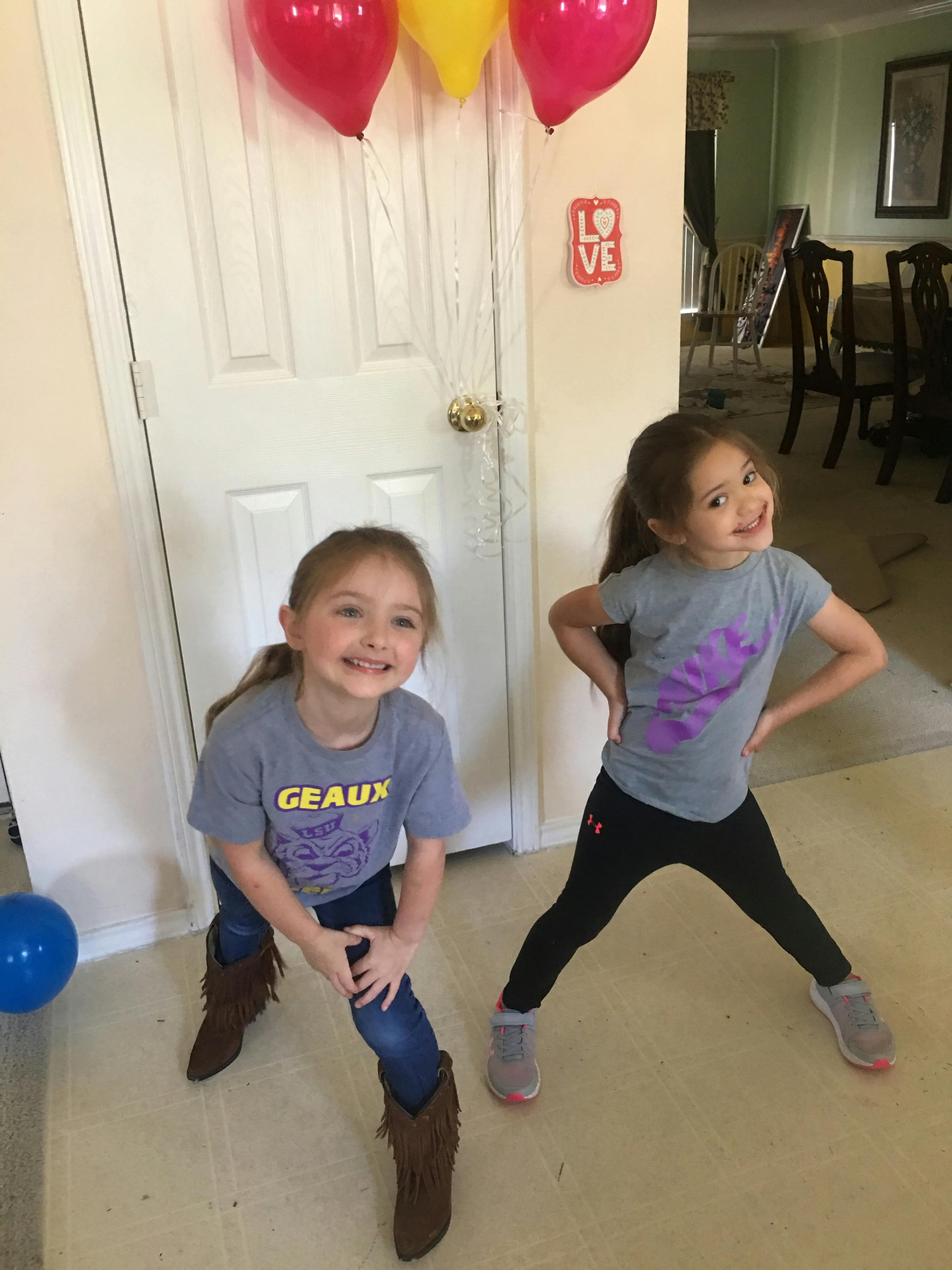 Two children posing in front of a door with balloons