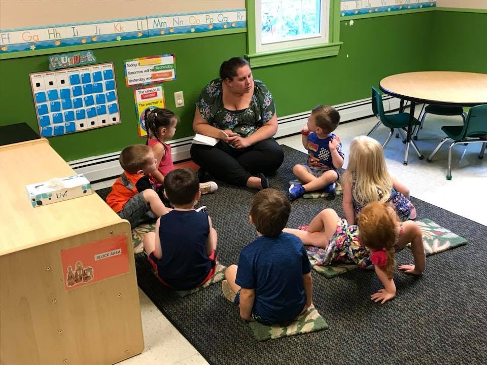 Adult and multiple children sitting on the floor in a classroom