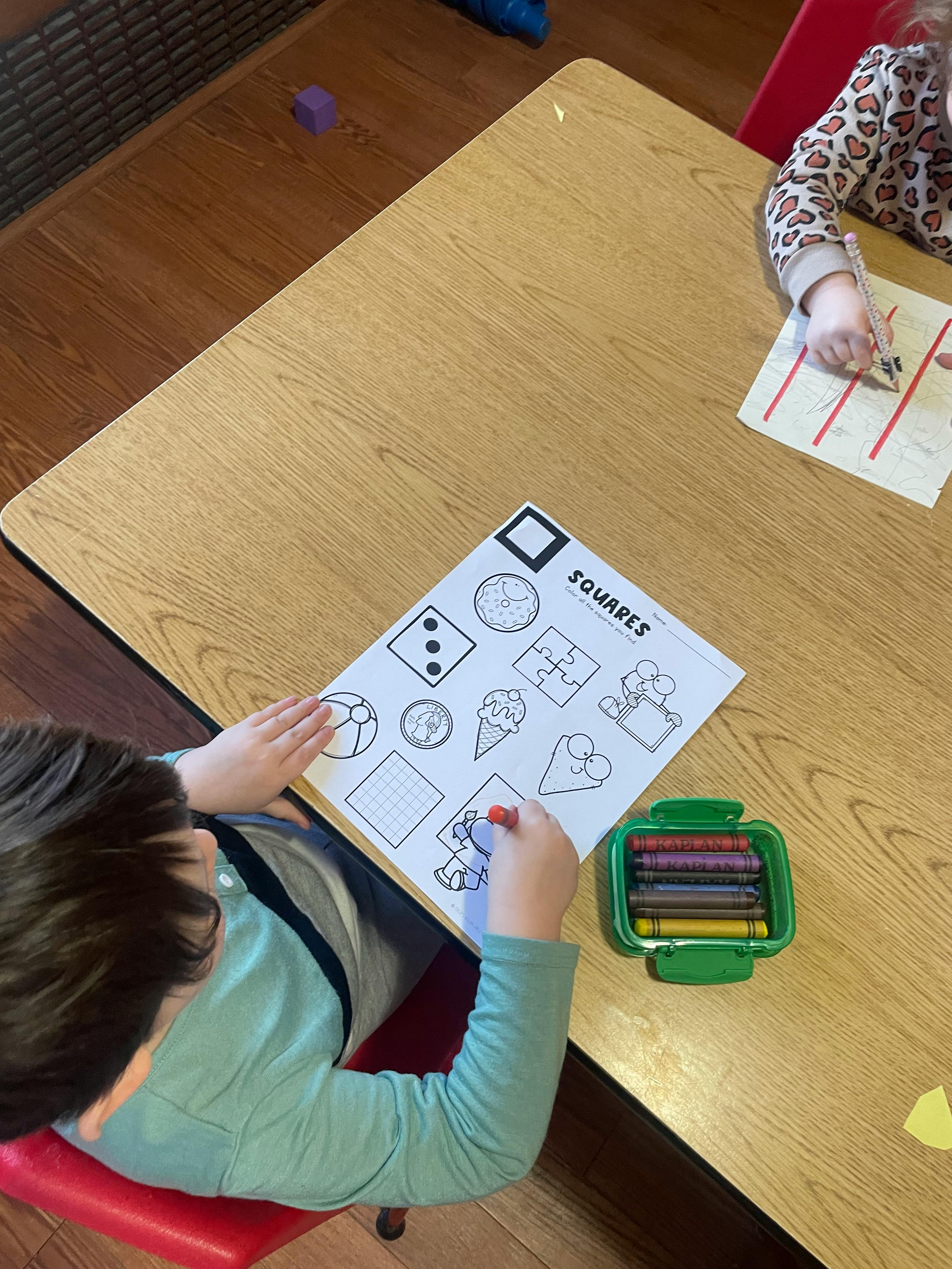 Child coloring a worksheet with shapes, text says "SQUARES"