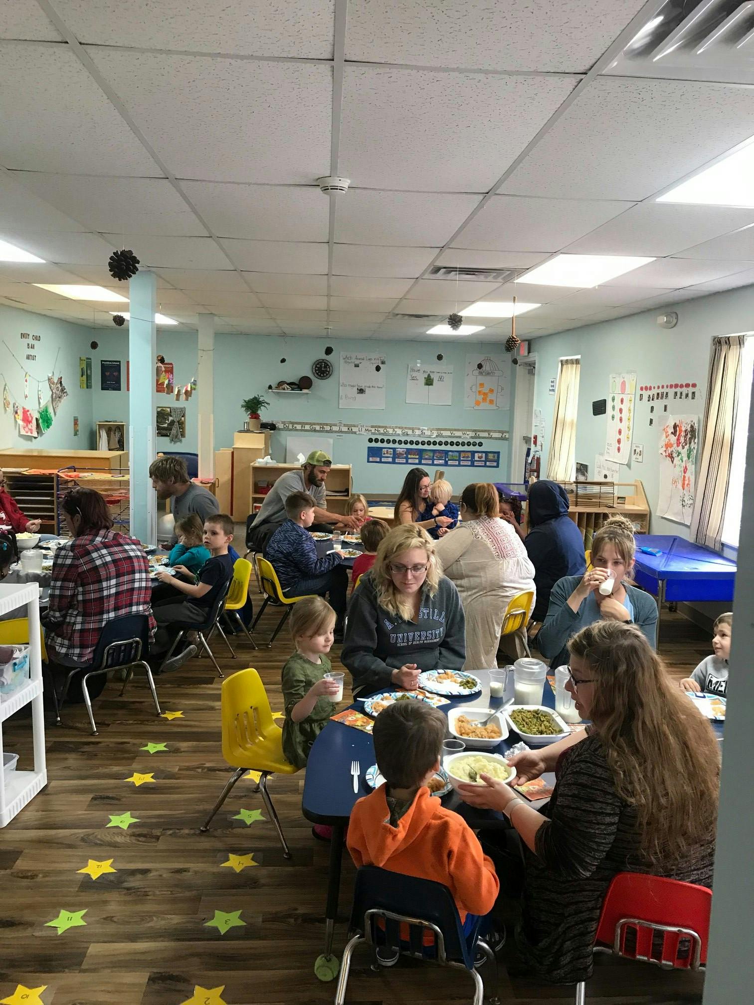 People and children eating at tables in a classroom