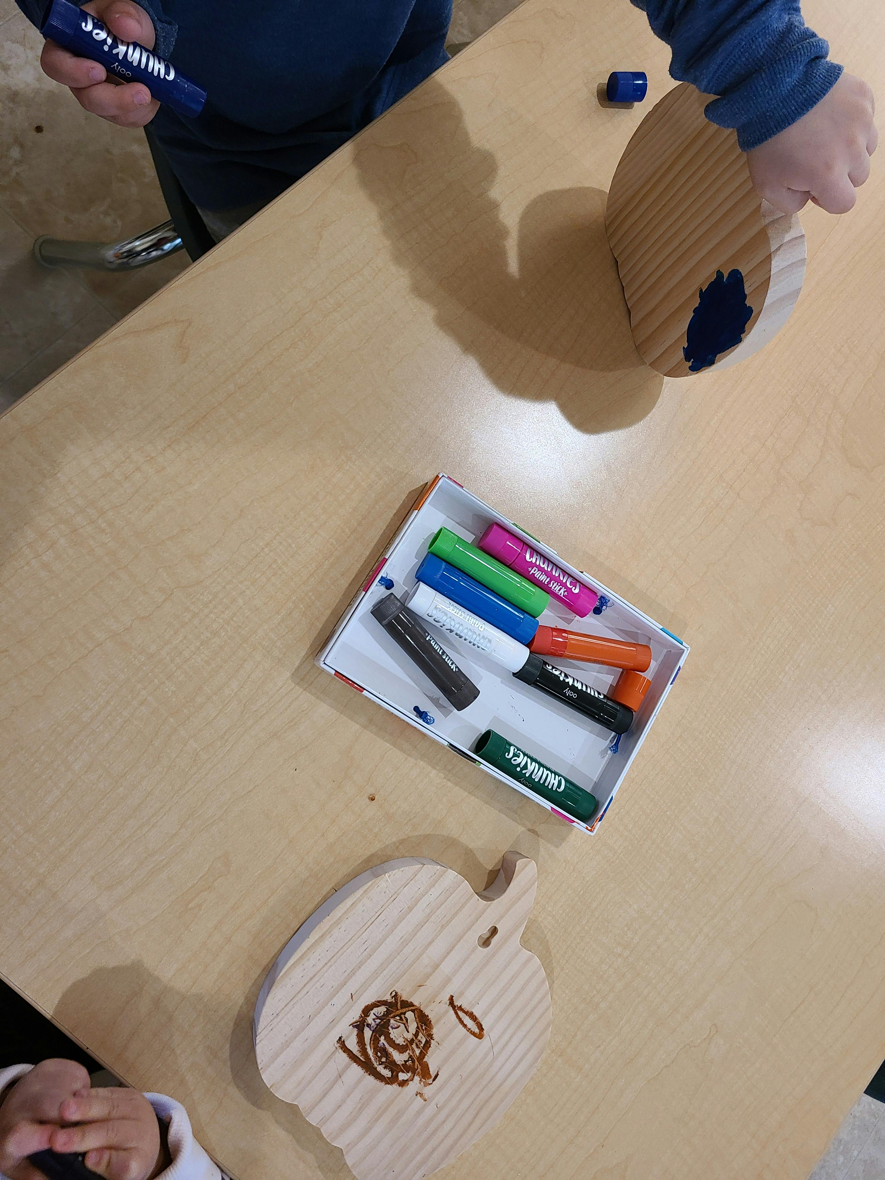 Person coloring a wooden apple shape with a marker