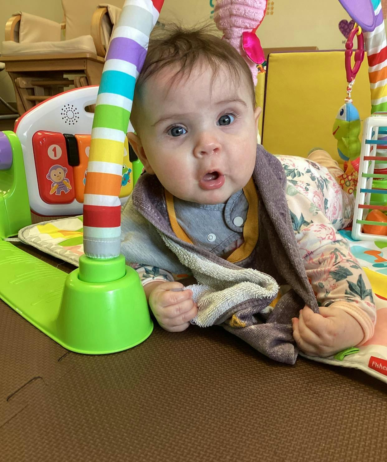 Child on stomach looking up next to a colorful play gym