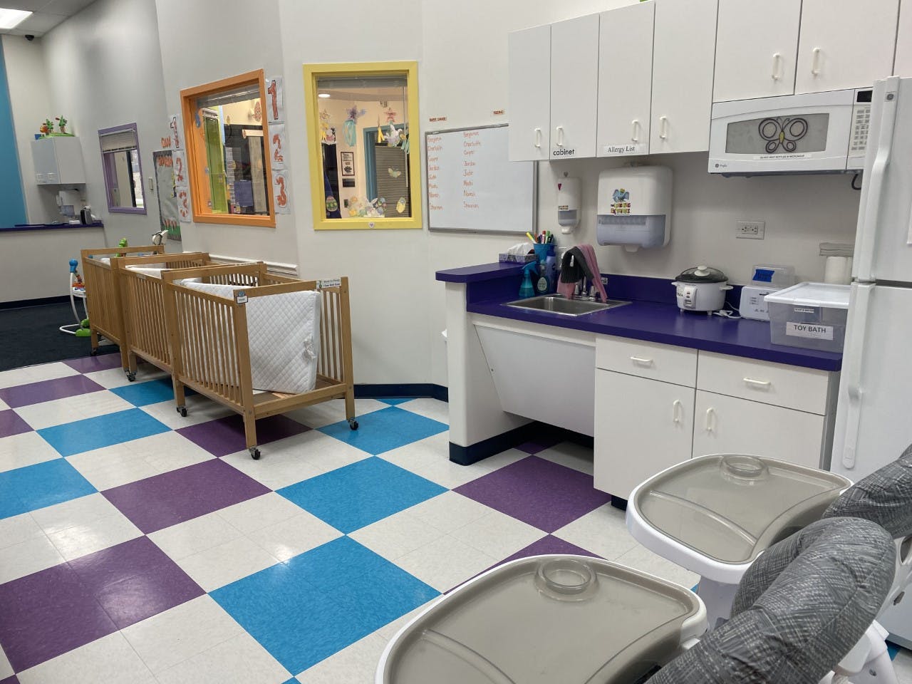 Room with cribs, a kitchen area, and checkered floor