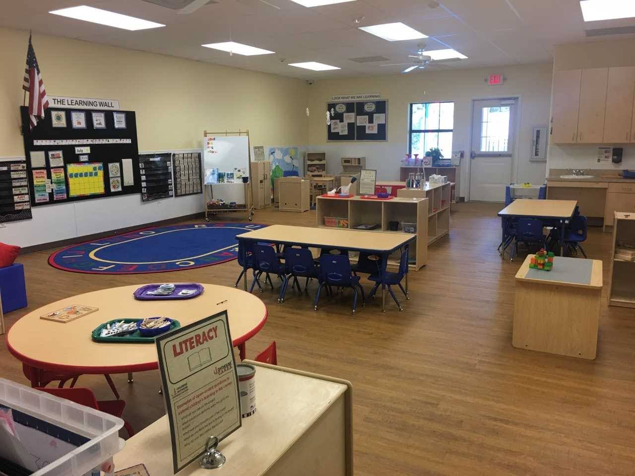 Empty classroom with tables, chairs, and a blue rug