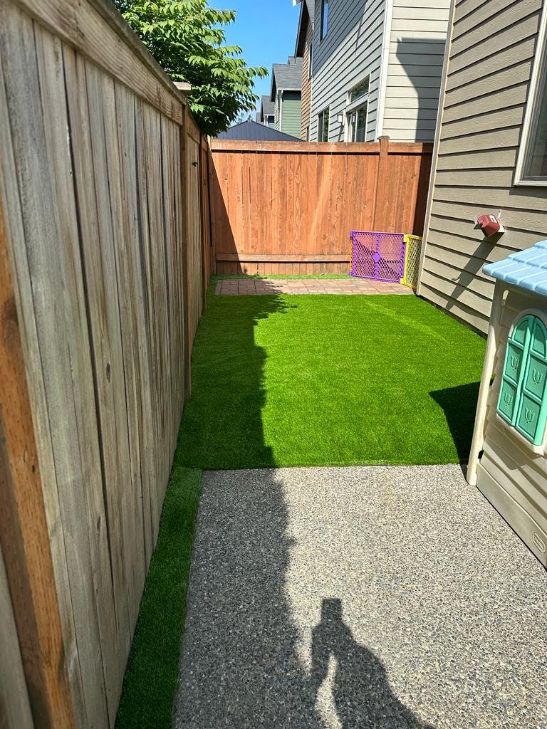 Narrow backyard with artificial turf, gravel path, and wooden fences
