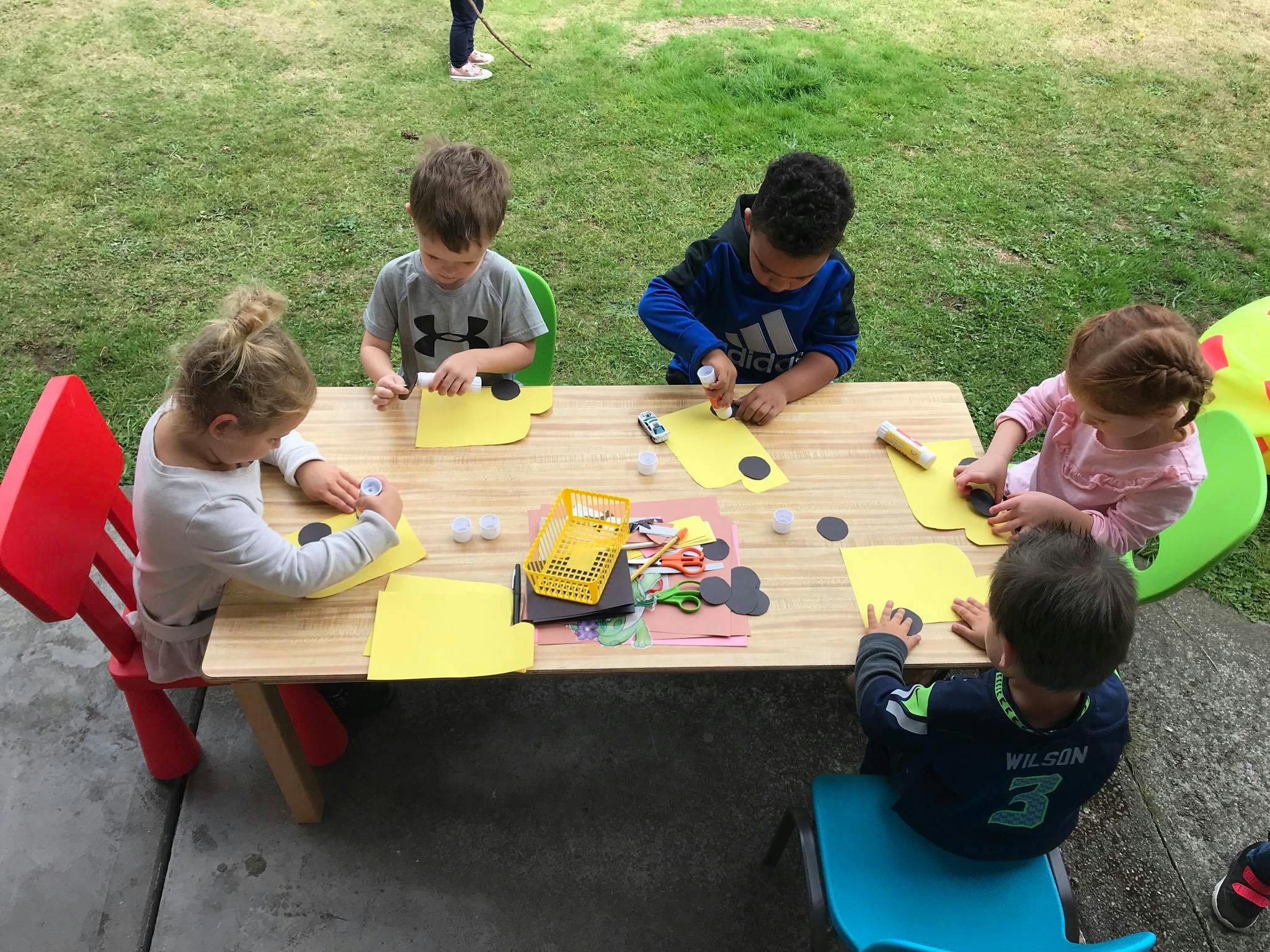 Children doing crafts at a table outdoors