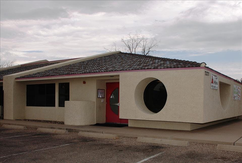 Single-story building with a red door and a large circular window