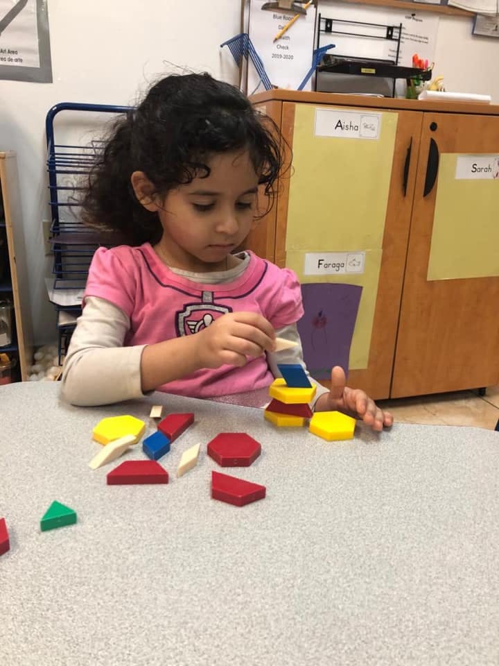 Child playing with colorful geometric blocks on a table