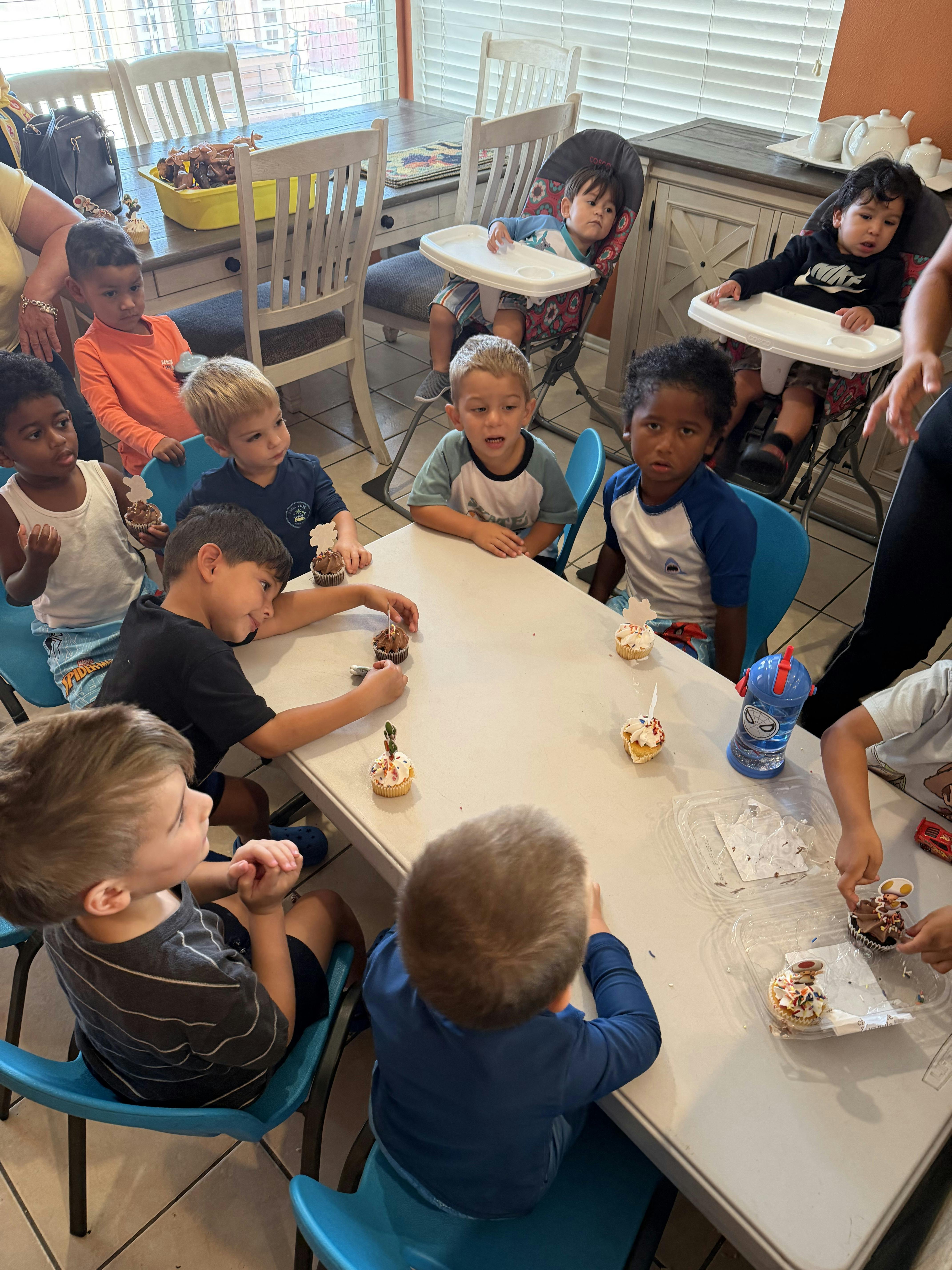 Group of children sitting at a table with cupcakes