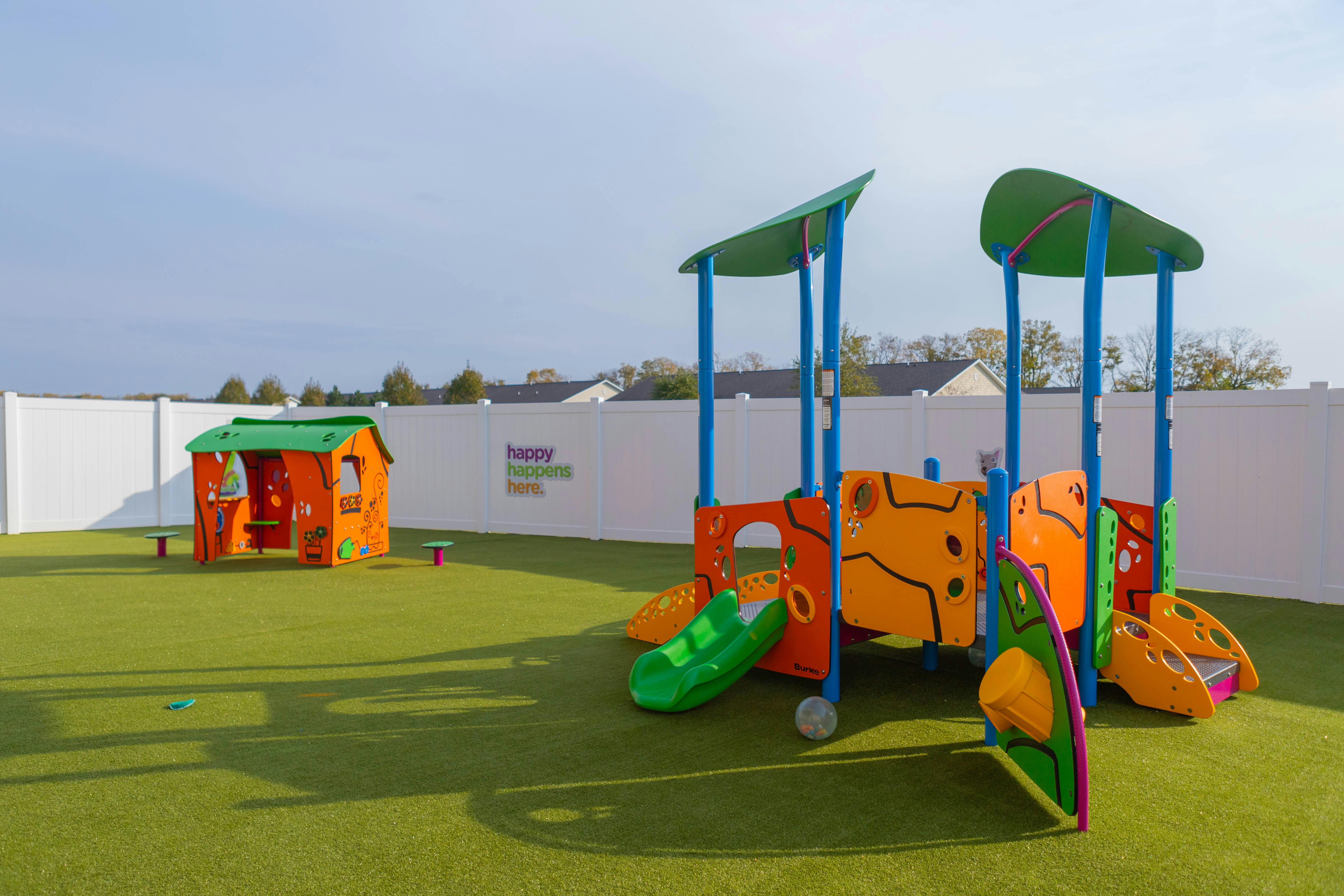 Playground with colorful play structure and small playhouse on green turf