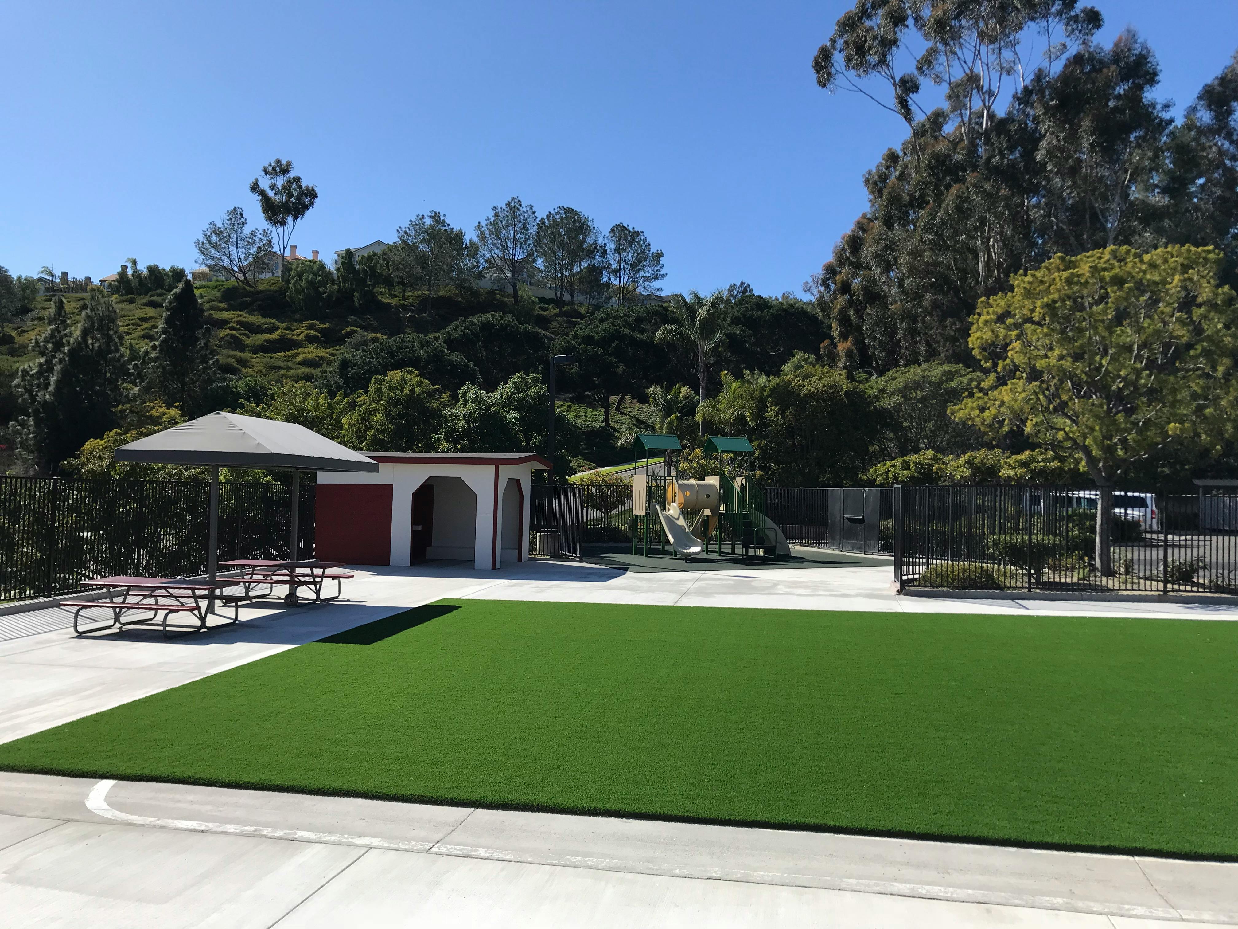 Outdoor area with artificial turf, picnic tables, and a building