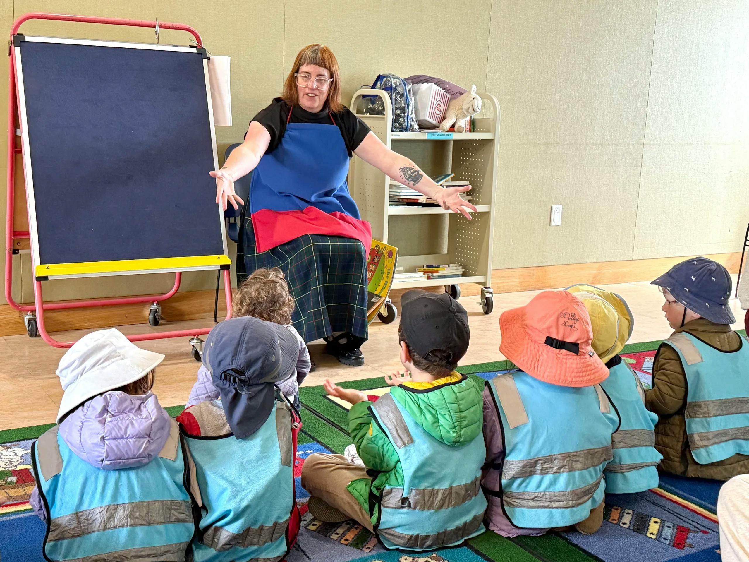 Person speaking to a group of children sitting on the floor