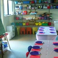 Classroom with tables set with plates and shelves of supplies