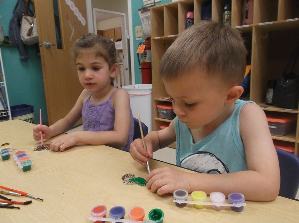 Two children painting at a table