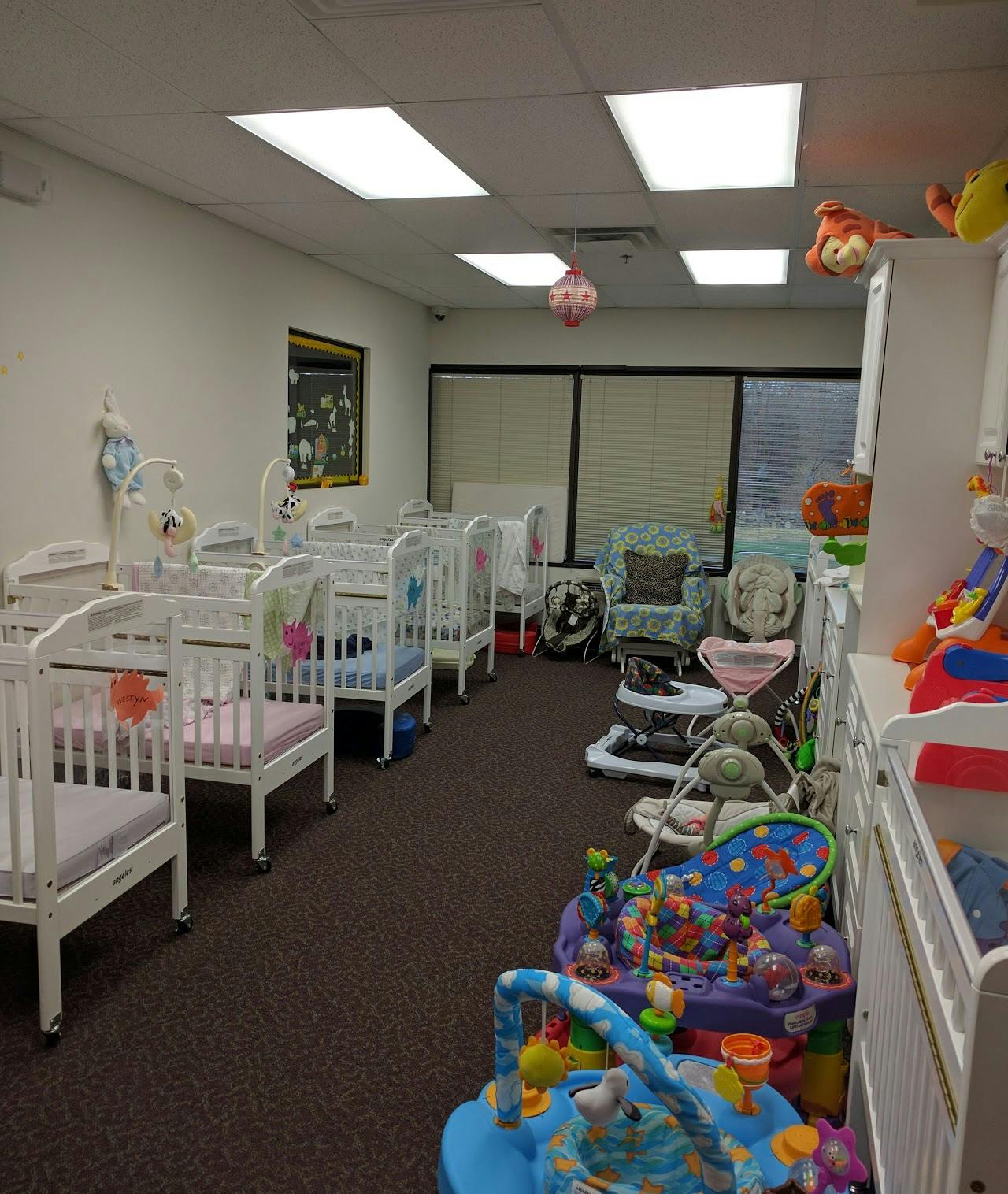 Room with multiple white cribs and baby play equipment