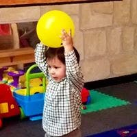 Child holding a yellow ball above their head