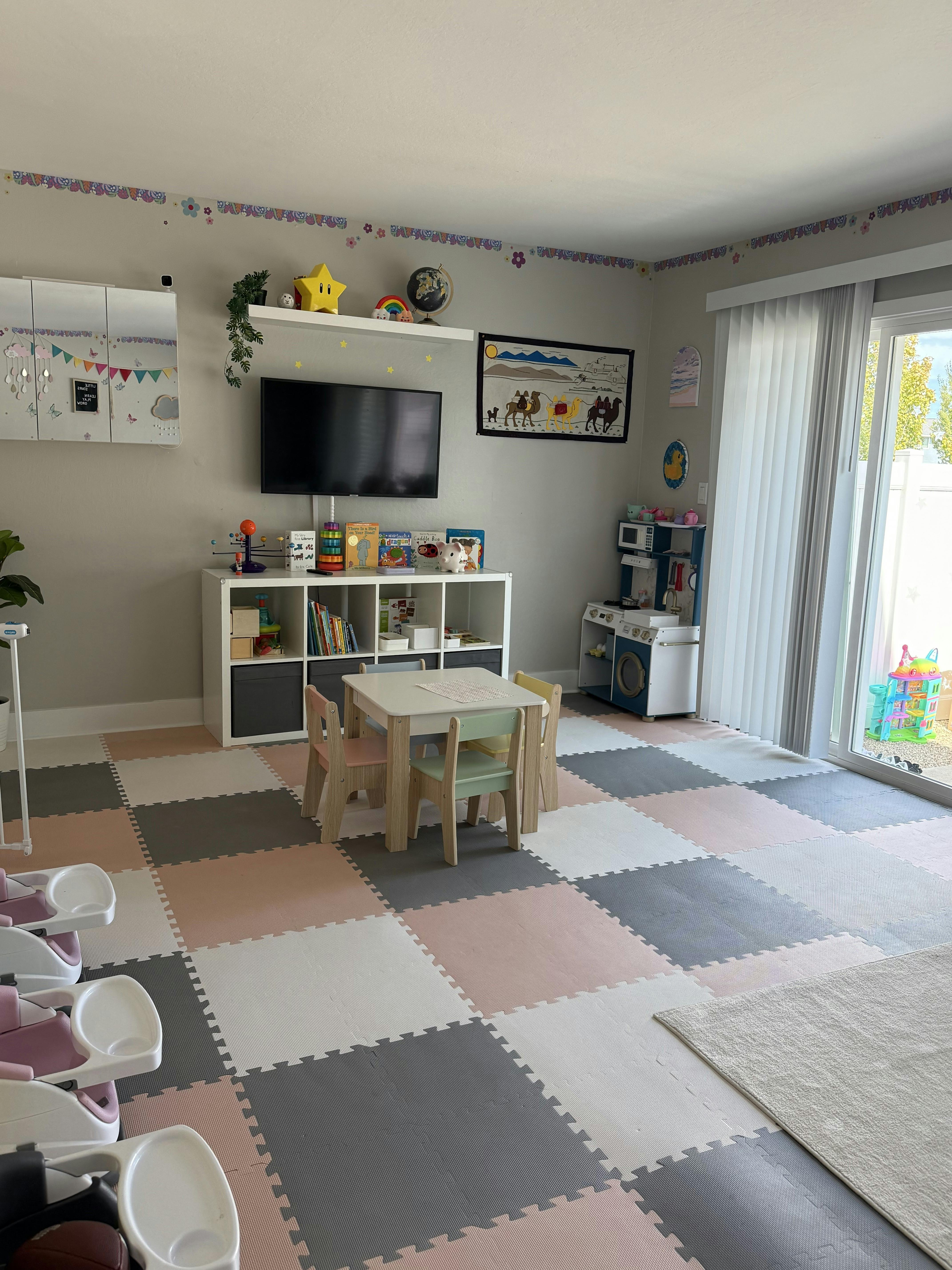 Playroom with floor mats, a small table with chairs, toys, and a television
