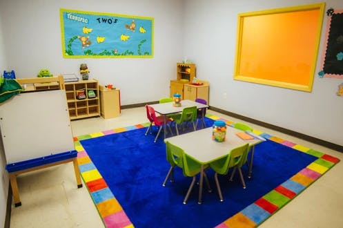 Classroom with small tables and chairs on a blue rug
