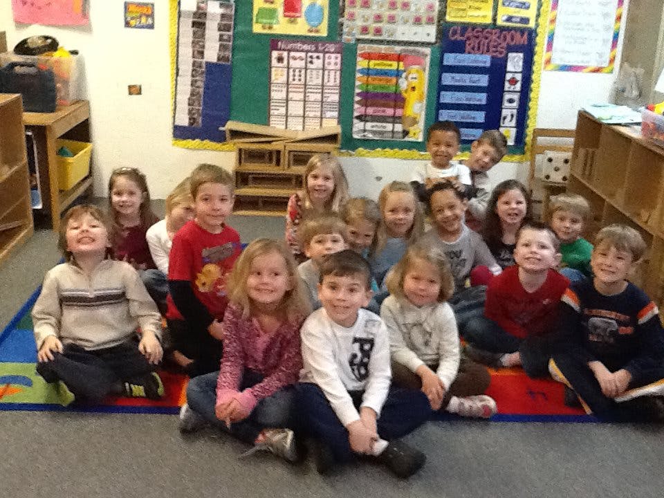 Group of children sitting on a rug in a classroom