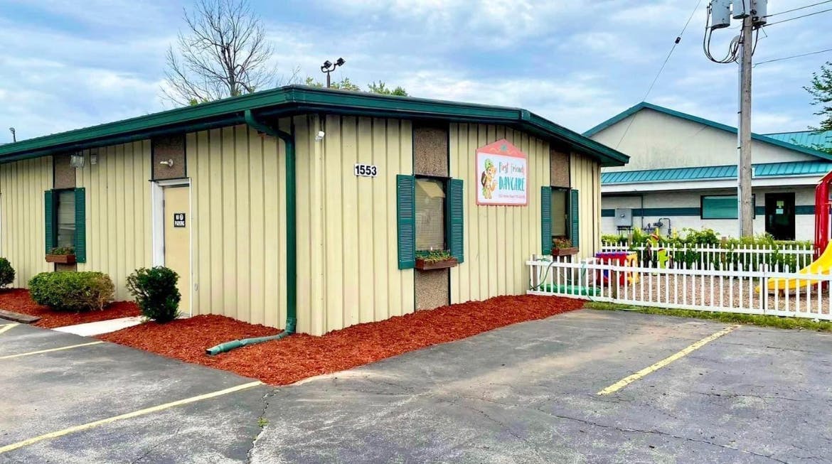 Exterior of a building with a white picket fence and playground equipment