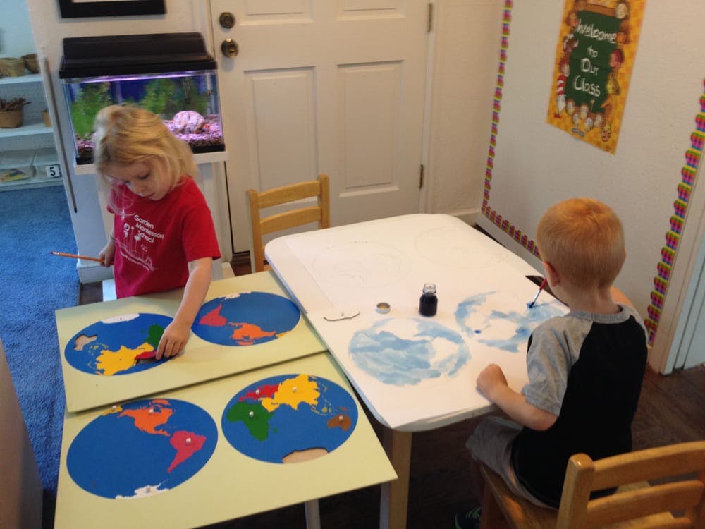 Child working on a puzzle of the world map, another child painting a globe