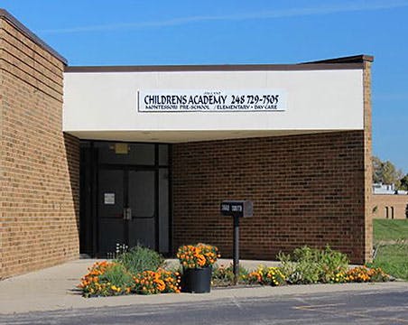 Entrance to a brick building with "CHILDRENS ACADEMY" sign above the door