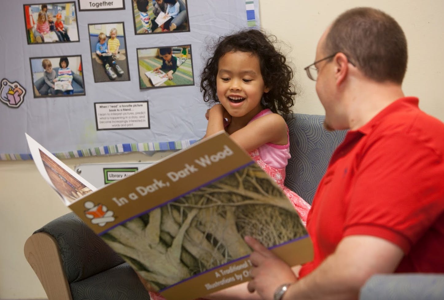 Person reading a book titled "In a Dark, Dark Wood" to a child