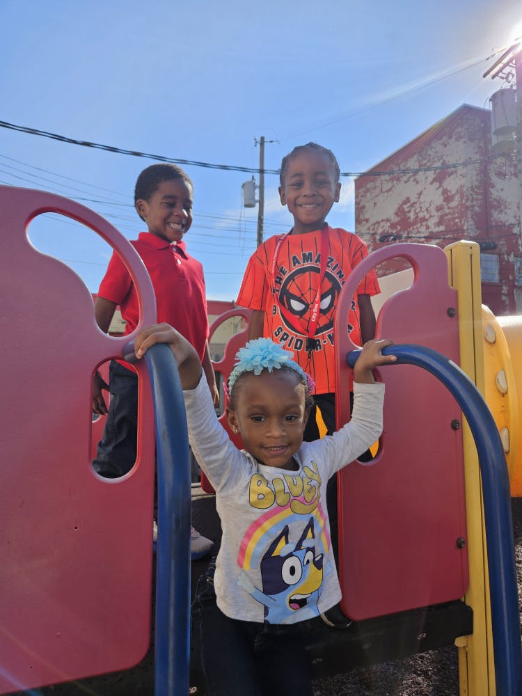 Three children playing on a playground structure