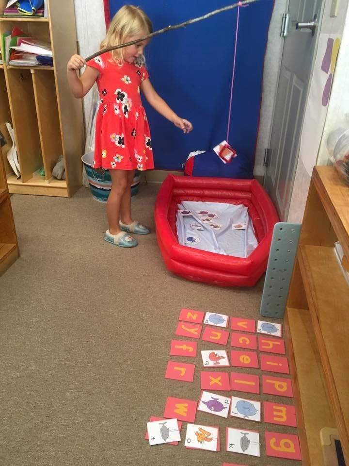Child playing a fishing game with a stick and string over an inflatable pool