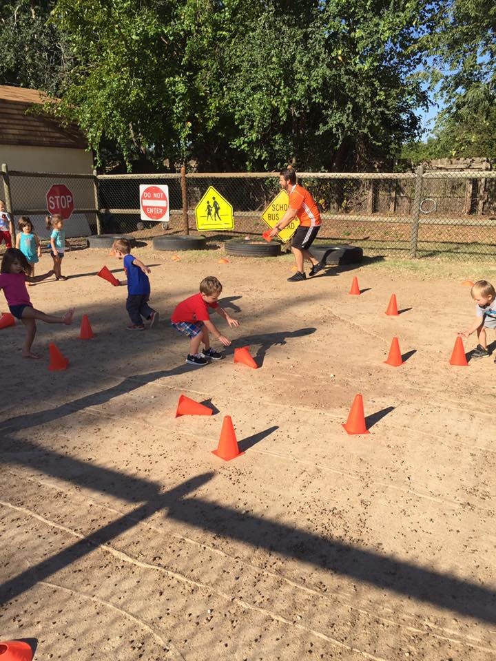 Adult and children playing with orange cones in a sandy area