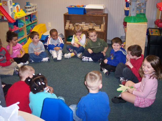 Children sitting in a circle on the floor in a classroom