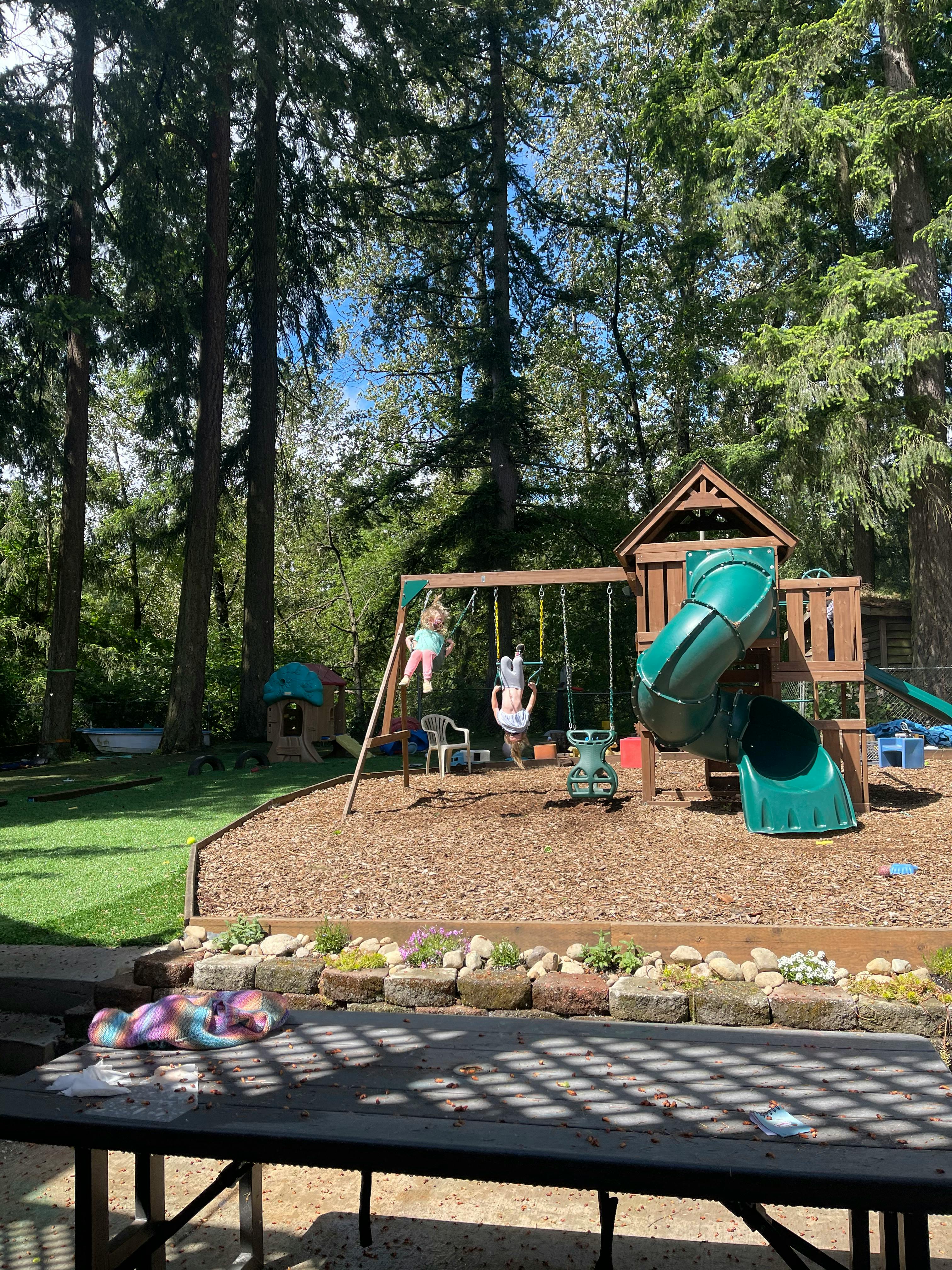Two children on swings in a backyard playground