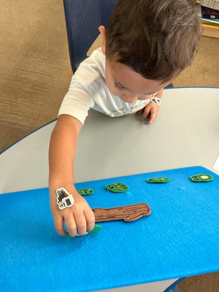 Child playing with a blue felt board and cut-out shapes