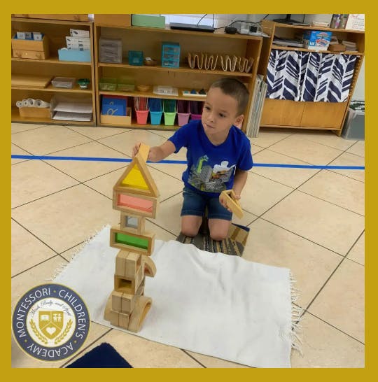 Child kneeling on a mat and stacking wooden building blocks