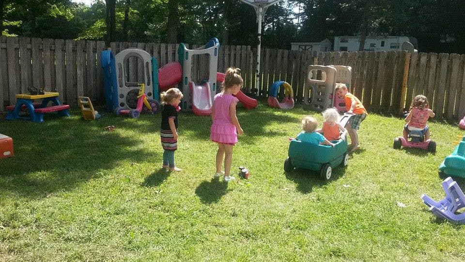 Children playing in a grassy yard with toys