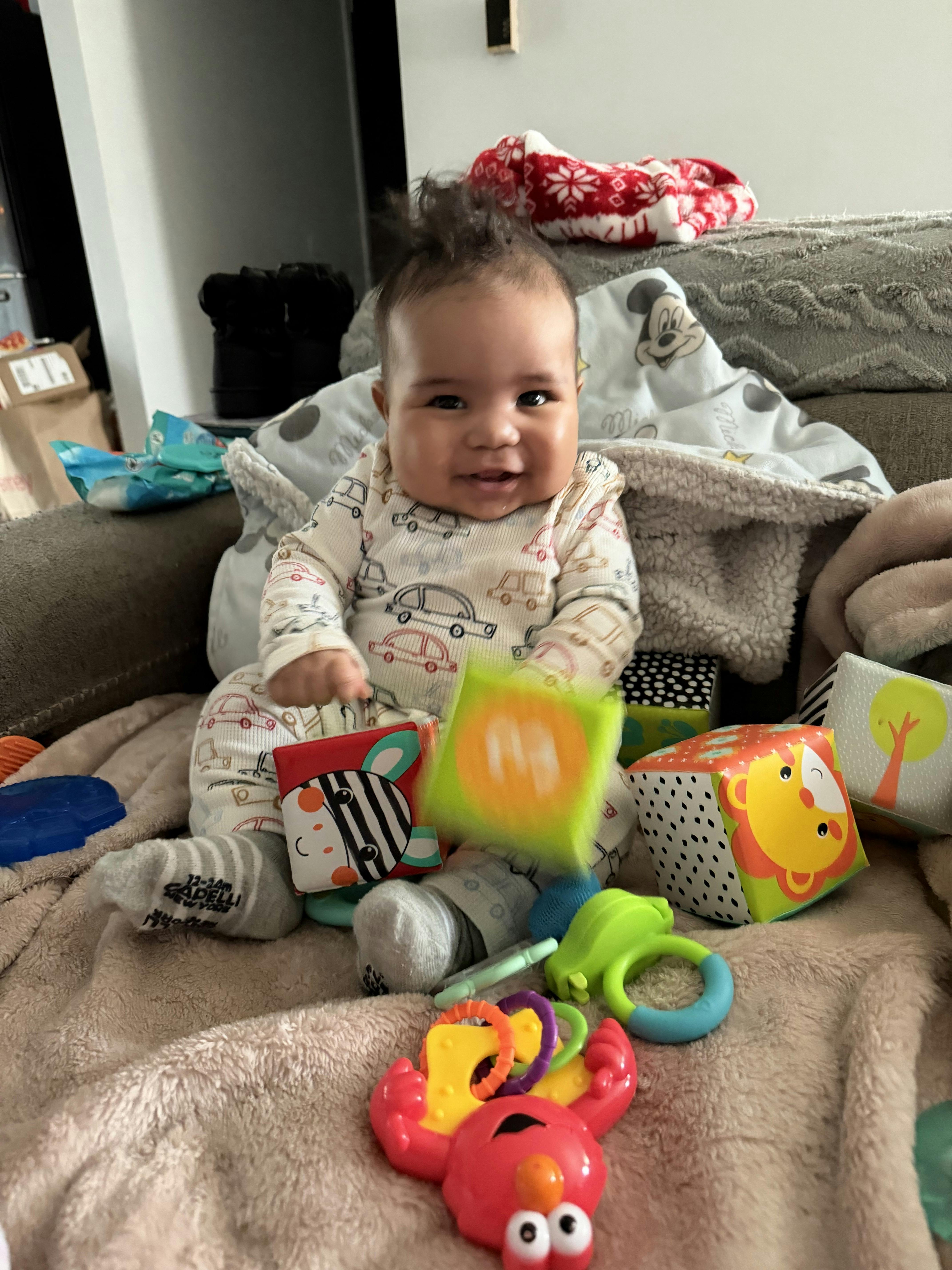 Smiling child playing with colorful soft blocks and toys on a blanket