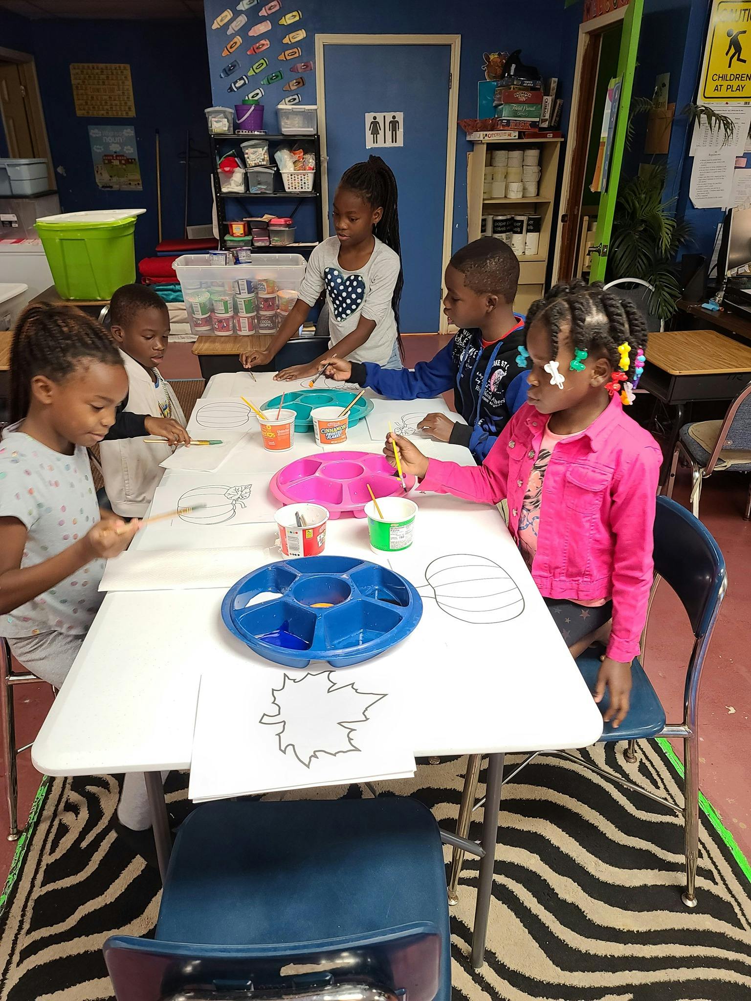 Children painting at a table in a classroom
