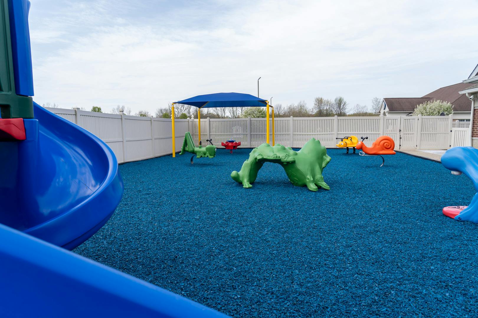 Playground with blue slide, green climbing structure, and swings