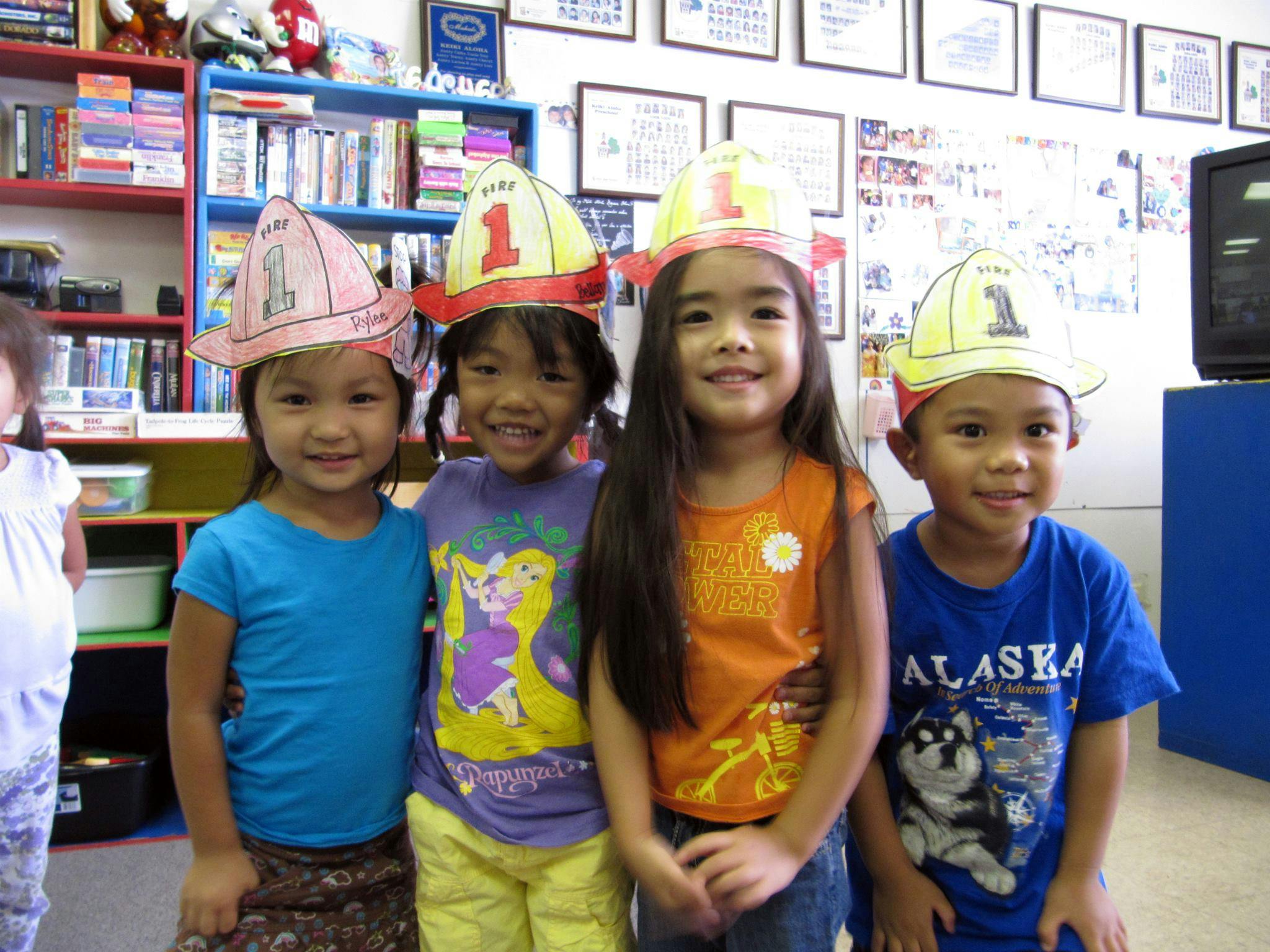 Four children wearing paper firefighter hats