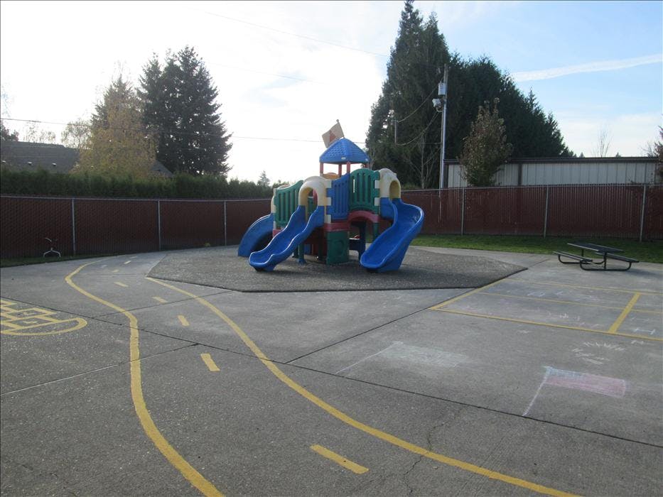 Playground with climbing structure and slides, and a painted road on concrete