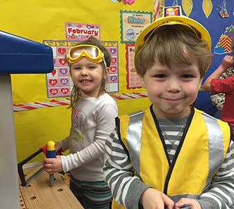 Two children playing dress-up in a classroom