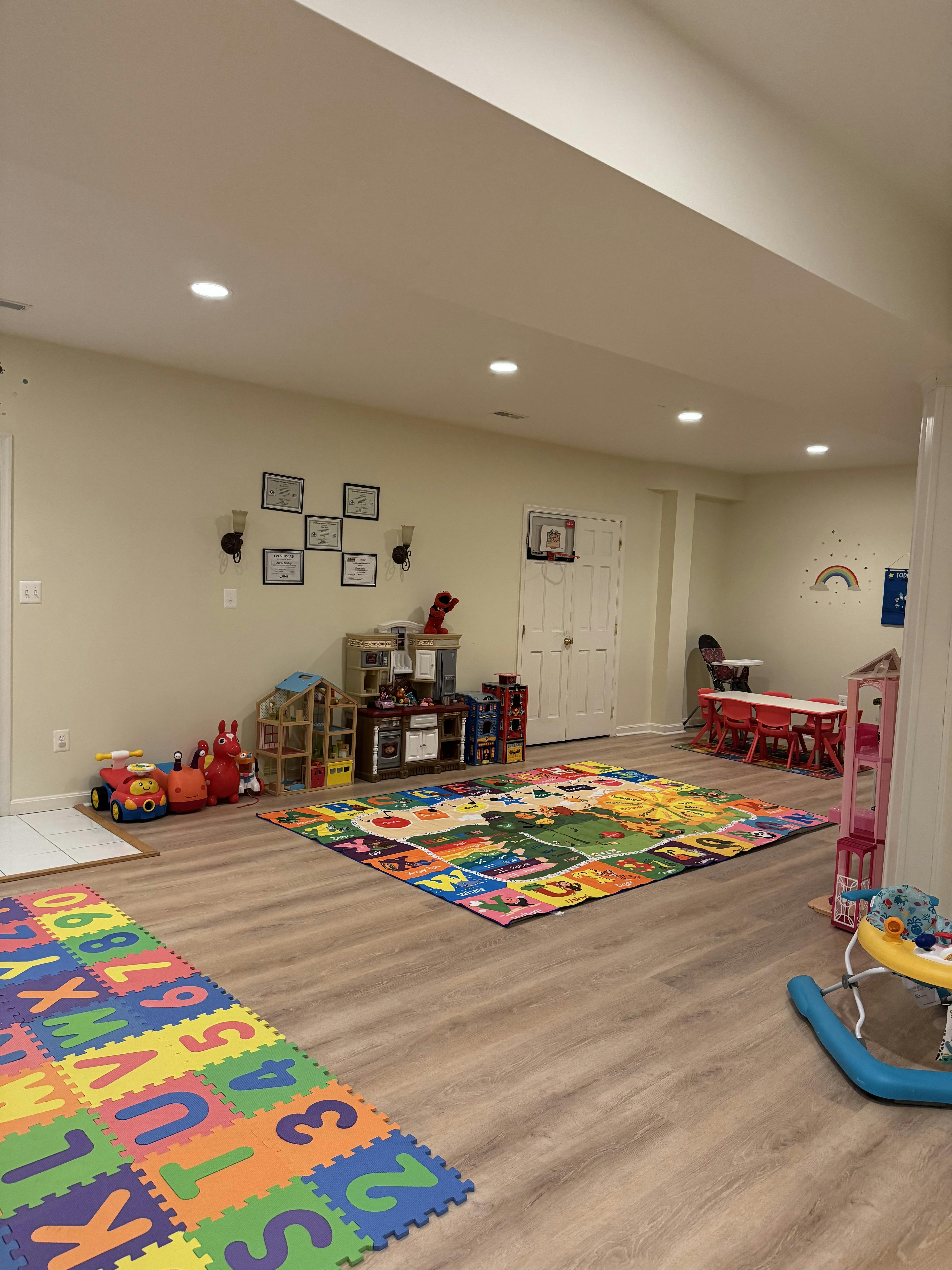 Playroom with colorful alphabet and road map rugs, toys, and small table with chairs