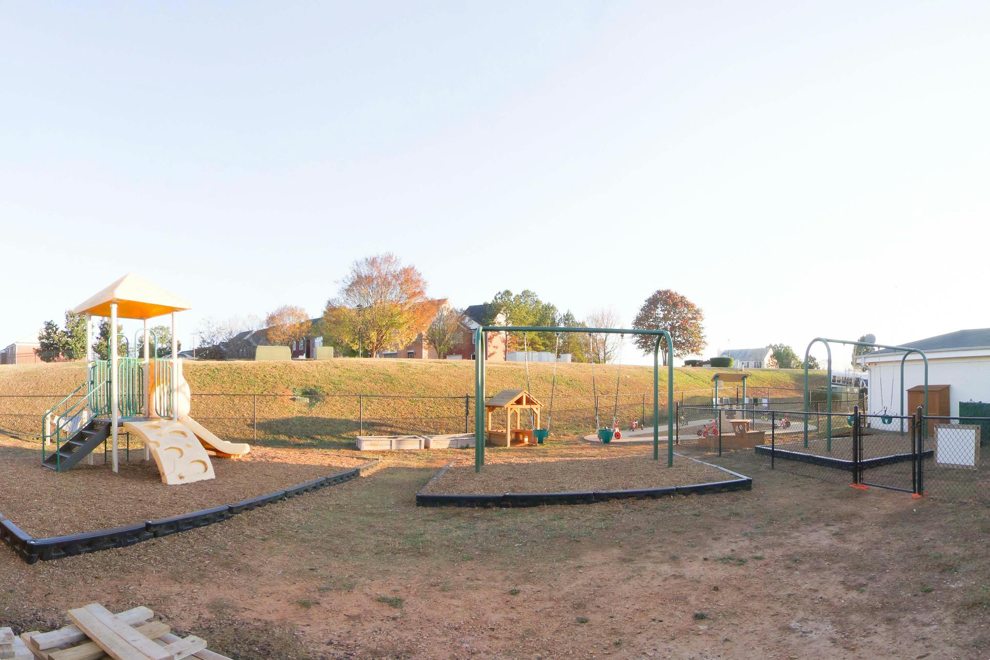 Empty outdoor playground with slides, swings, and a small playhouse